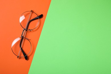 Photo of Glasses in stylish frame on color background, top view. Space for text