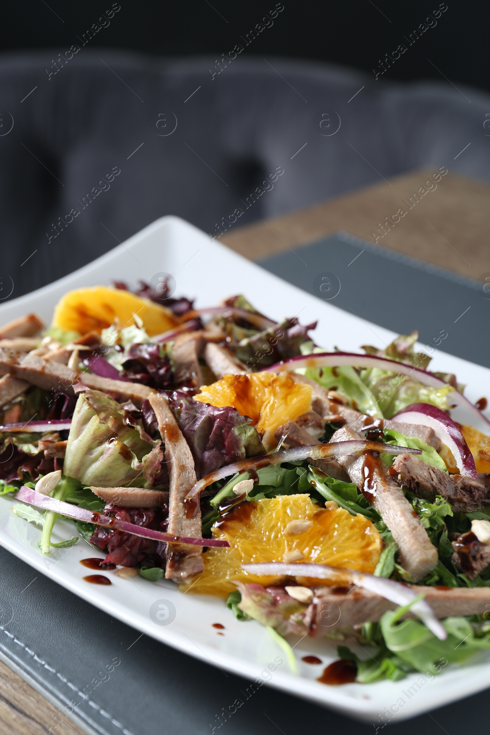 Photo of Delicious salad with beef tongue, orange and onion on wooden table, closeup