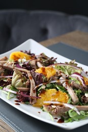 Delicious salad with beef tongue, orange and onion on wooden table, closeup