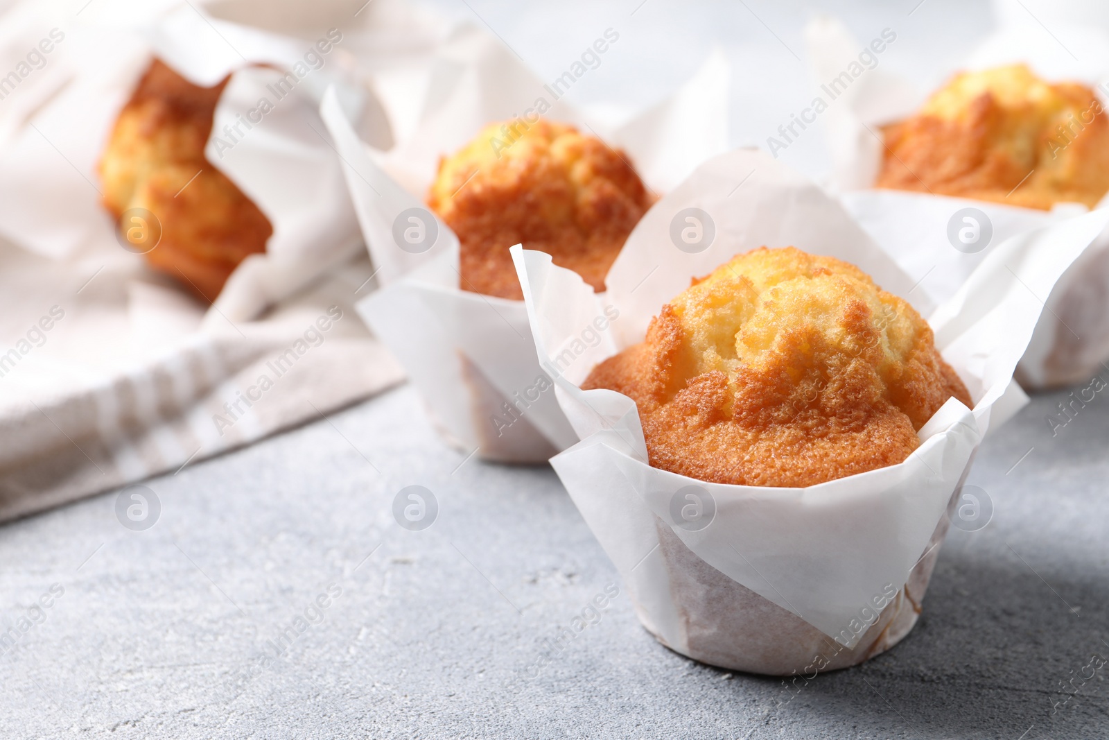 Photo of Delicious sweet muffins on light grey textured table, closeup. Space for text