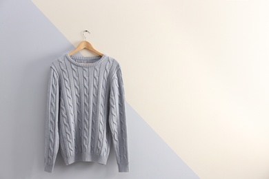 Photo of Hanger with stylish sweater on color wall. Space for text