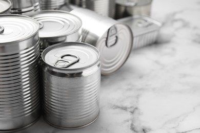 Photo of Many closed tin cans on white marble table, closeup. Space for text