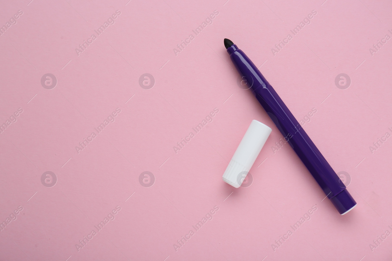 Photo of Bright purple marker and cap on light pink background, flat lay. Space for text