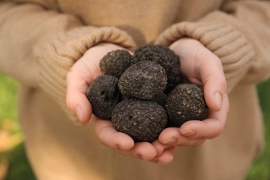 Photo of Woman holding fresh truffles in hands outdoors, closeup
