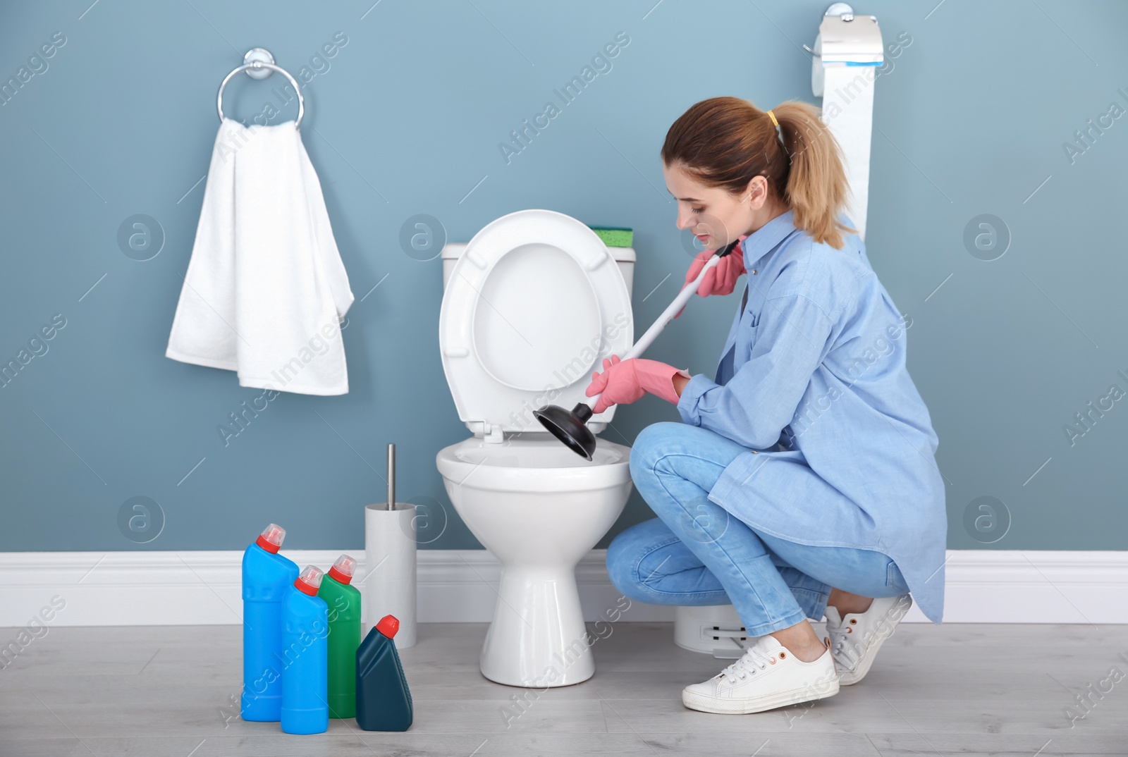 Photo of Woman cleaning toilet bowl in bathroom