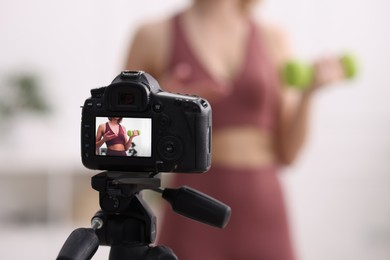 Photo of Sports blogger with dumbbell recording fitness lesson at home, focus on camera. Space for text