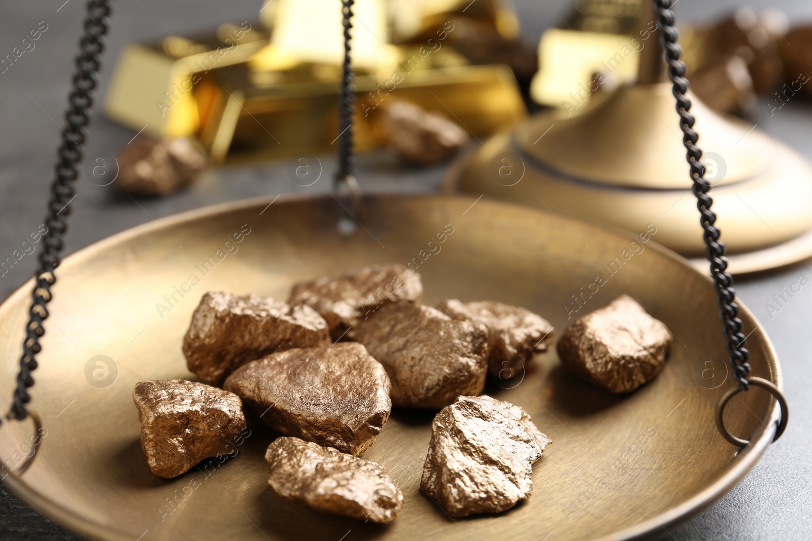 Photo of Scale pan with gold lumps on grey table, closeup