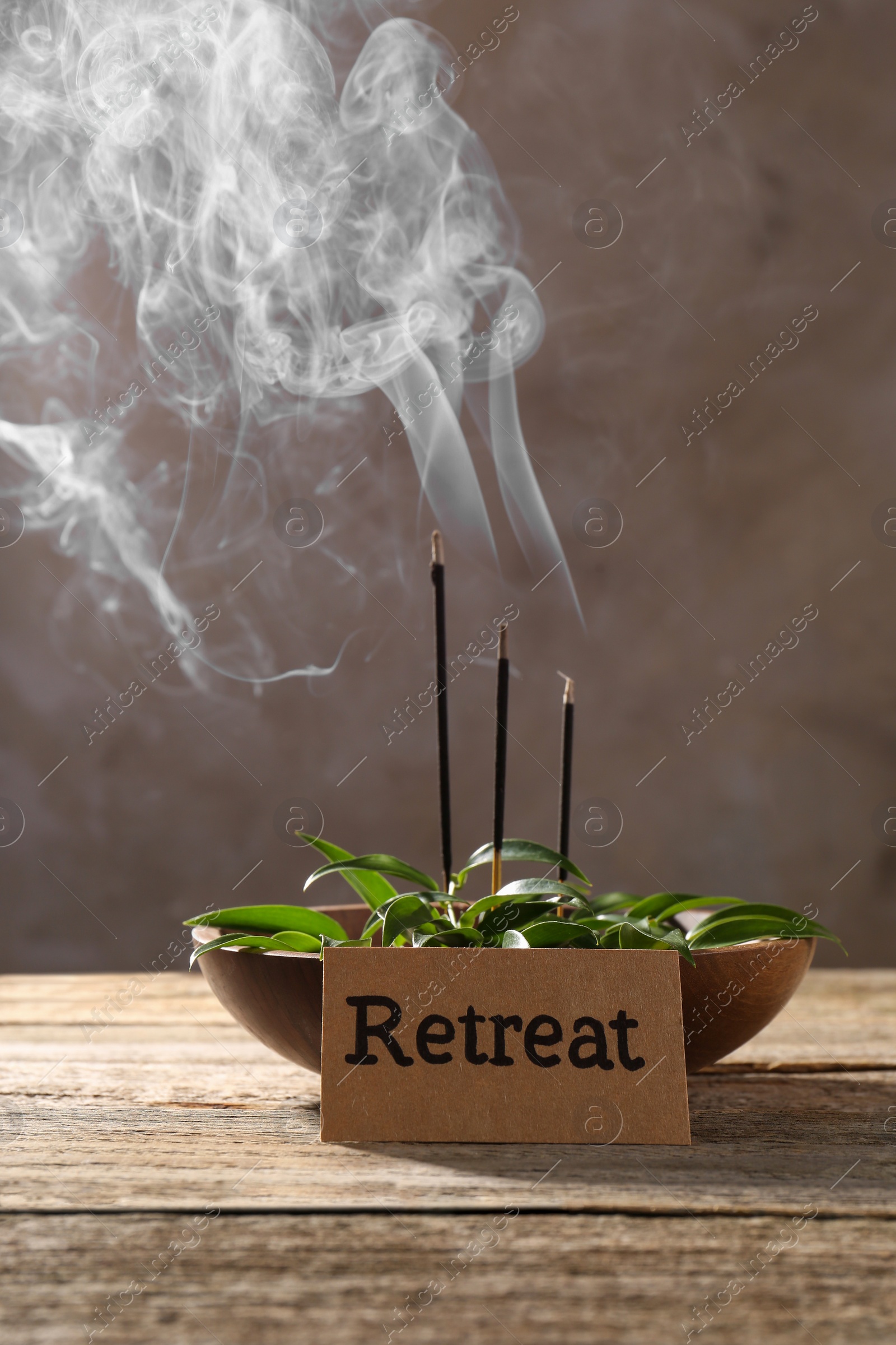 Photo of Card with word Retreat, green leaves and incense sticks on wooden table