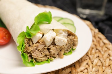 Photo of Delicious tortilla wrap with tuna on wicker mat, closeup