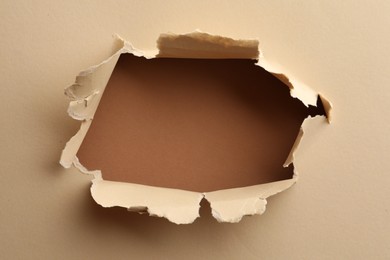 Hole in light beige paper on brown background
