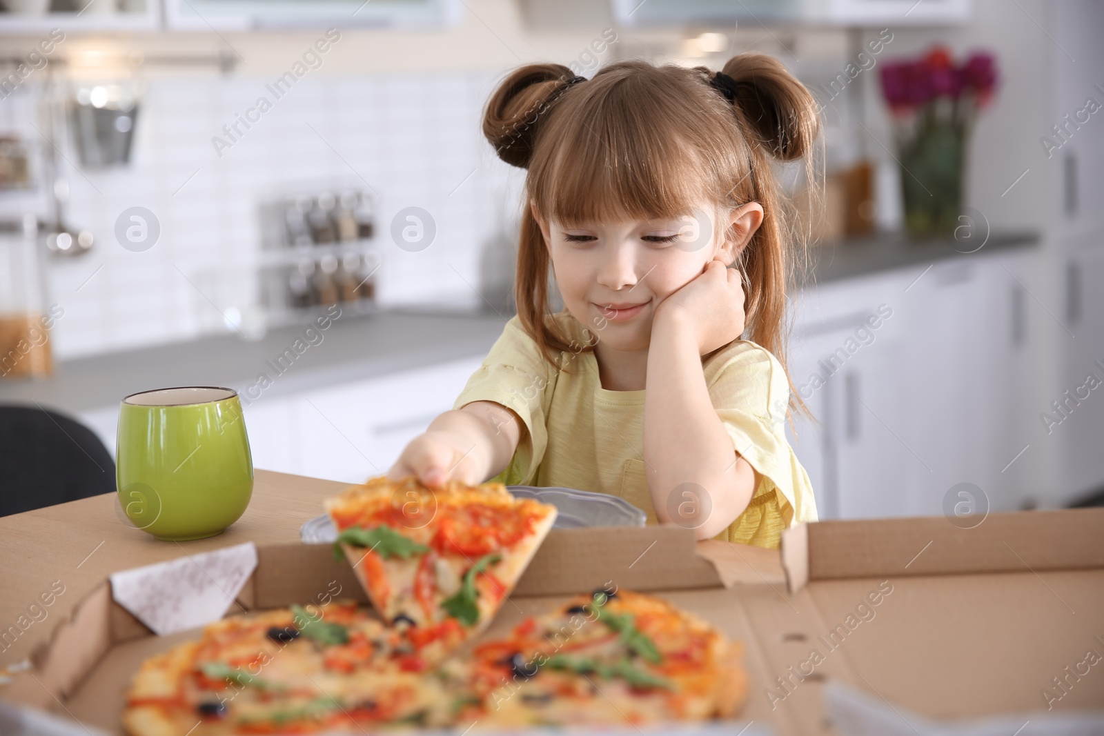 Photo of Cute little girl eating tasty pizza at home