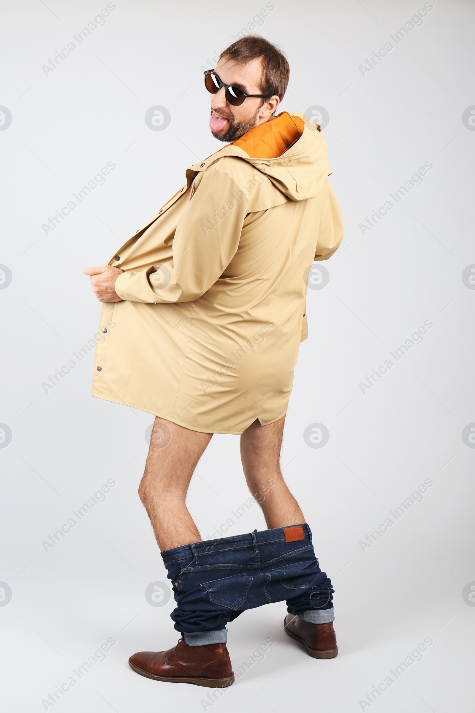 Photo of Exhibitionist exposing naked body under coat on light background