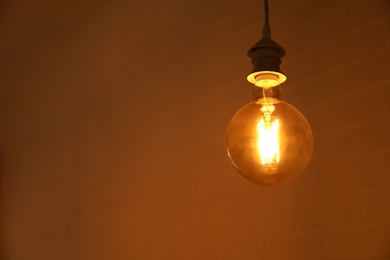 Photo of Lamp bulb near brick wall. Space for text