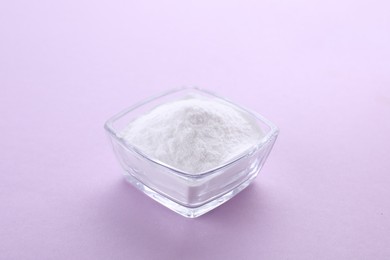 Photo of Bowl of sweet powdered fructose on light purple background