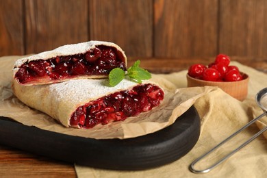 Delicious strudel with cherries on wooden table, closeup