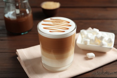 Photo of Glass with delicious caramel latte on table