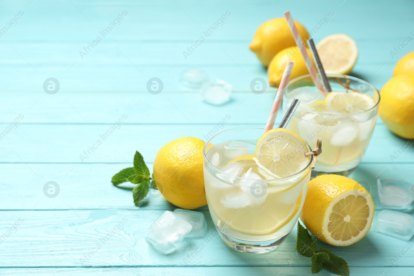 Photo of Natural lemonade and fresh fruits on light blue wooden table, space for text. Summer refreshing drink
