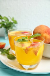 Photo of Tasty peach cocktail in glasses on table. Refreshing drink