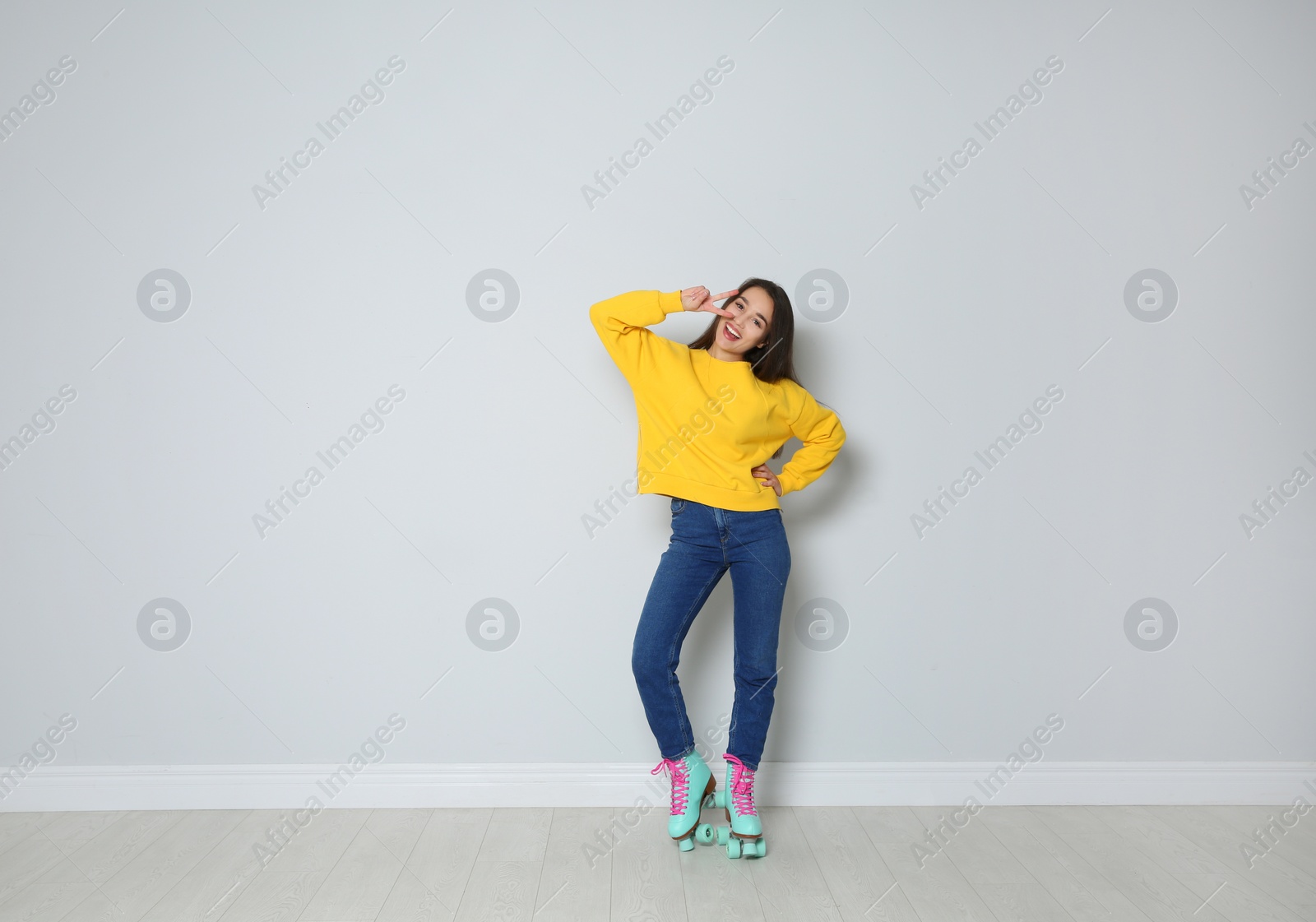 Photo of Full length portrait of young woman with roller skates near color wall