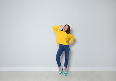 Photo of Full length portrait of young woman with roller skates near color wall