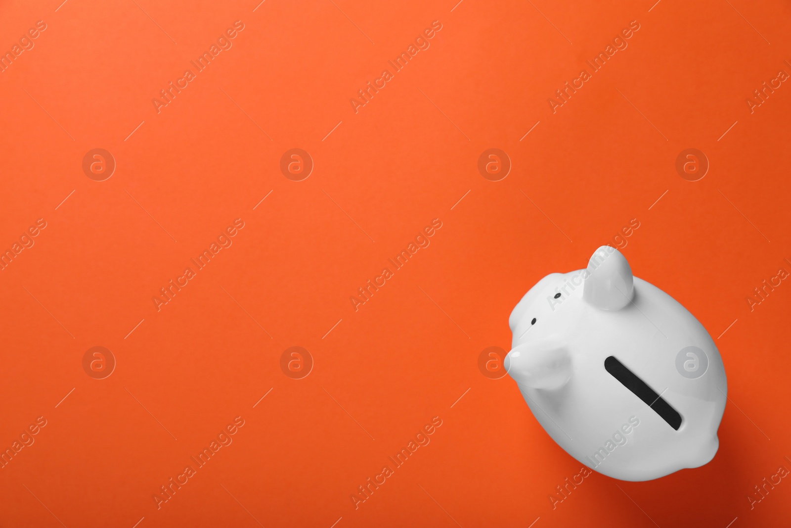 Photo of Ceramic piggy bank on orange background, top view with space for text. Financial savings