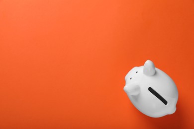 Photo of Ceramic piggy bank on orange background, top view with space for text. Financial savings