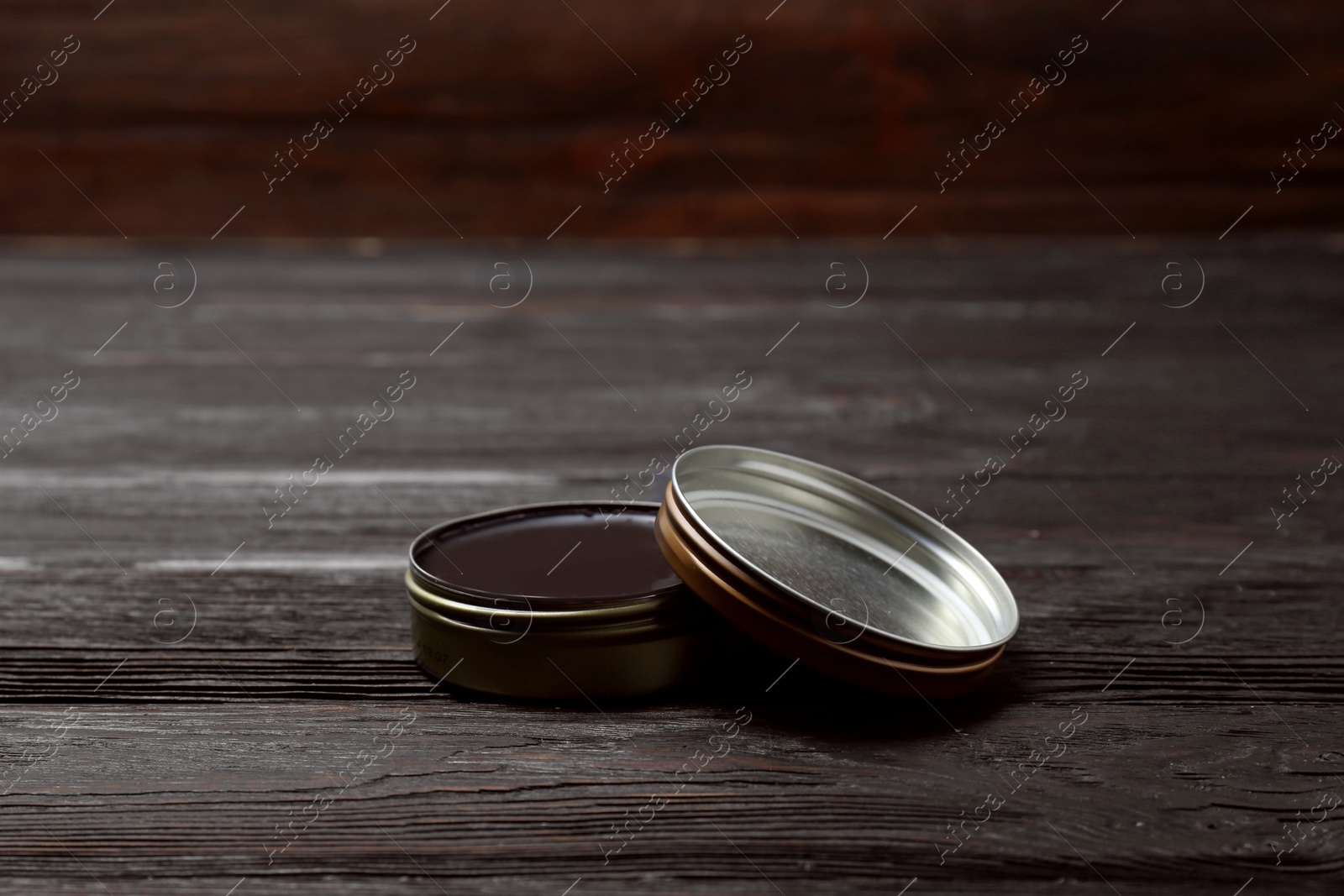Photo of Can of black shoe polish on wooden table. Footwear care item