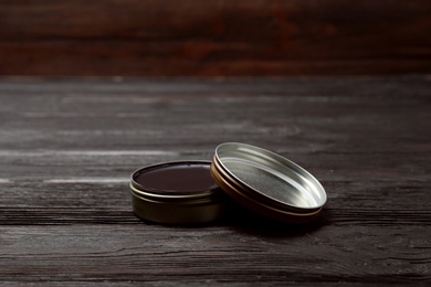 Photo of Can of black shoe polish on wooden table. Footwear care item