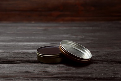 Can of black shoe polish on wooden table. Footwear care item