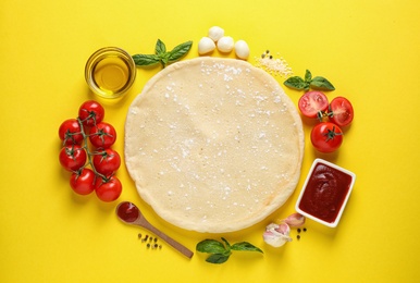 Photo of Flat lay composition with pizza crust and fresh ingredients on yellow background