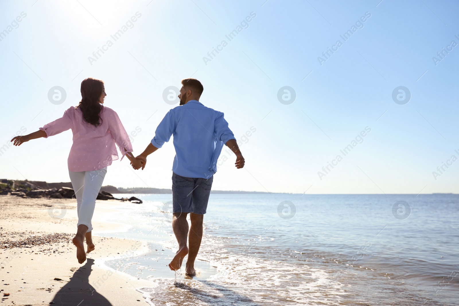 Photo of Happy young couple on beach near sea. Honeymoon trip