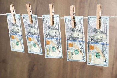 Photo of Dollar banknotes hanging on rope against wooden background