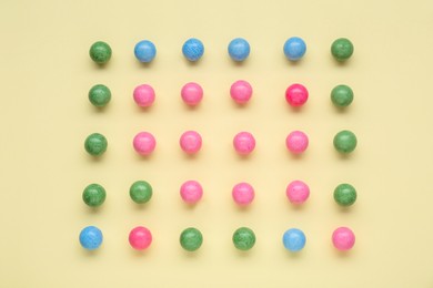 Many bright chewy gumballs on beige background, flat lay