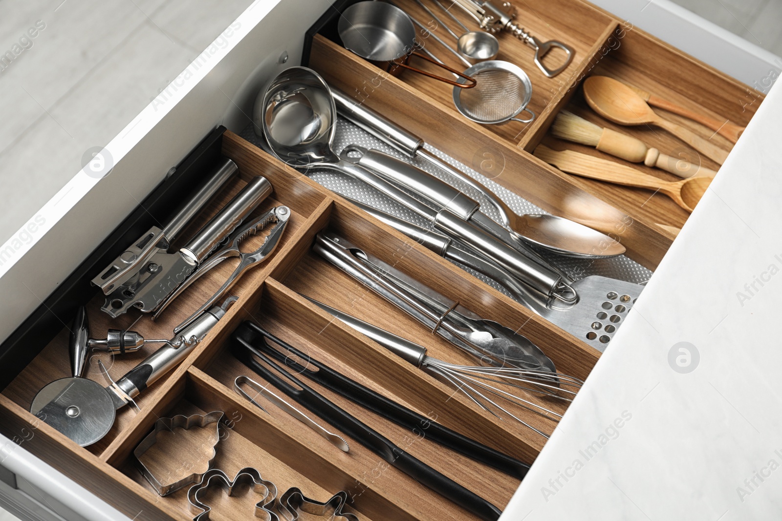 Photo of Different utensils in open desk drawer indoors, closeup