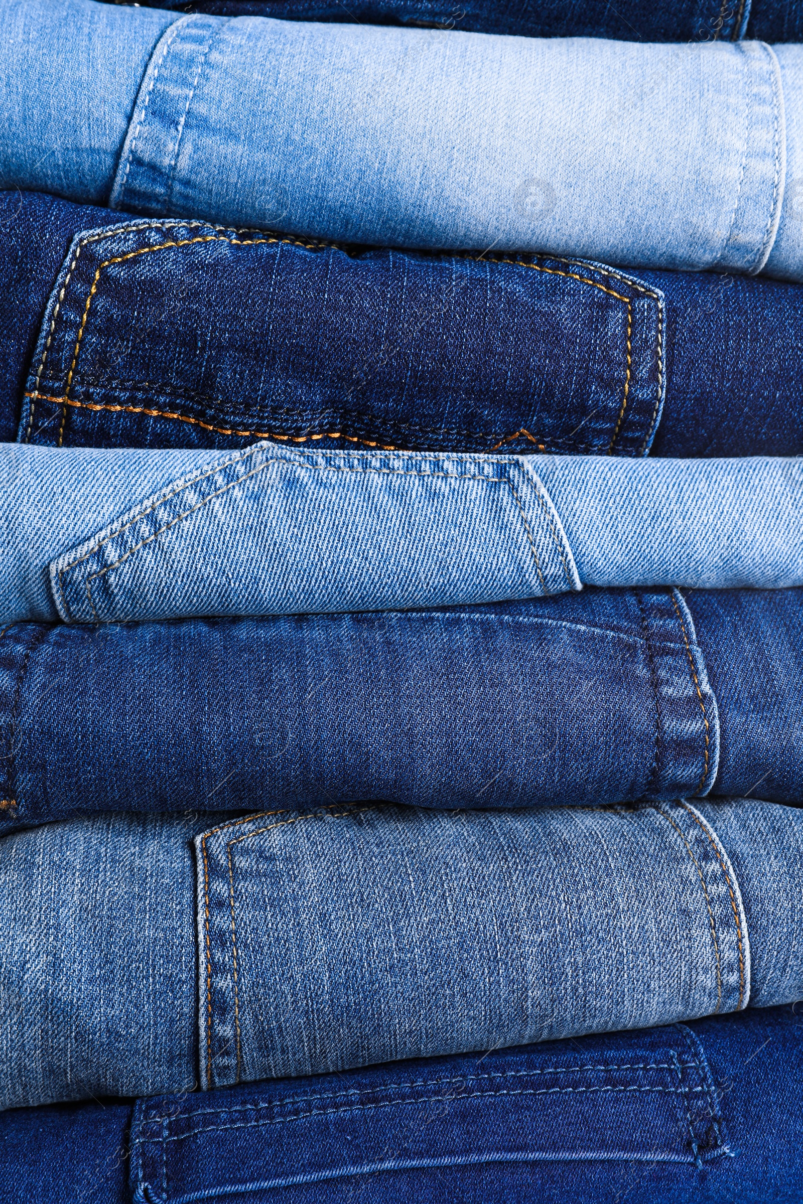 Photo of Stack of different jeans as background, closeup