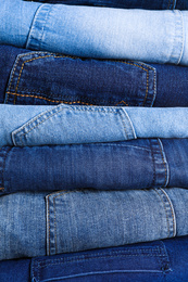 Stack of different jeans as background, closeup