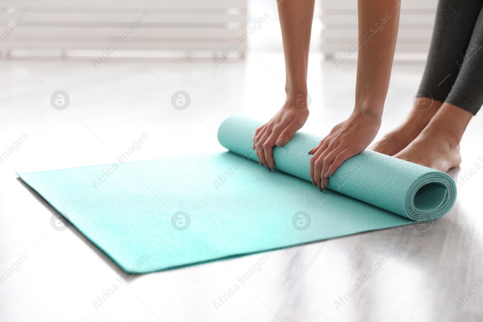Photo of Woman unrolling mat in yoga studio, closeup