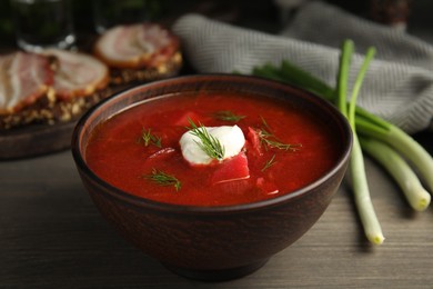 Photo of Clay bowl with Ukrainian borsch served on wooden table