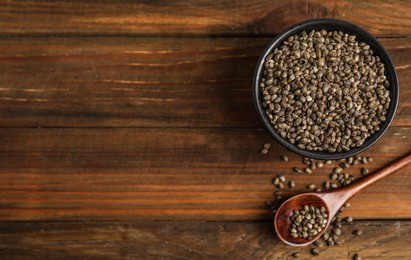 Bowl and spoon with organic hemp seeds on wooden table, flat lay. Space for text