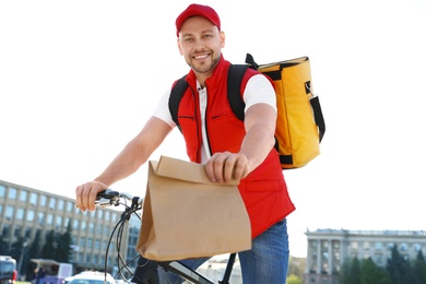 Male courier on bicycle delivering food in city