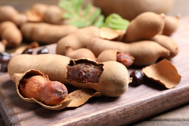 Photo of Delicious ripe tamarinds on wooden board, closeup