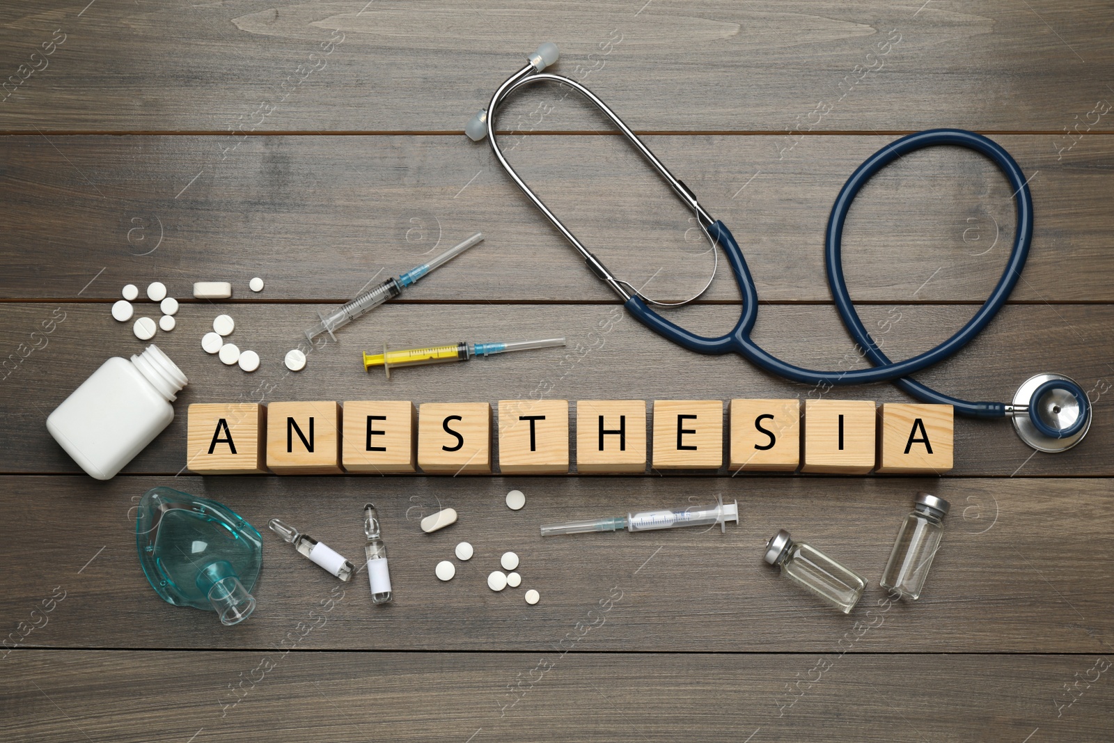 Photo of Flat lay composition with word Anesthesia made of cubes and drugs on wooden table