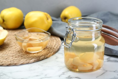 Photo of Delicious quince drink and fresh fruits on white marble table