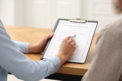 Photo of Notary consulting senior man about Last Will and Testament in office, closeup