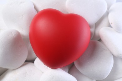 Photo of Decorative heart on white pebble stones, closeup