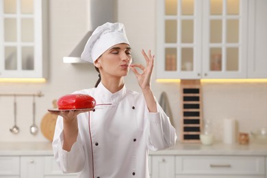 Photo of Professional confectioner with cake showing delicious gesture in kitchen
