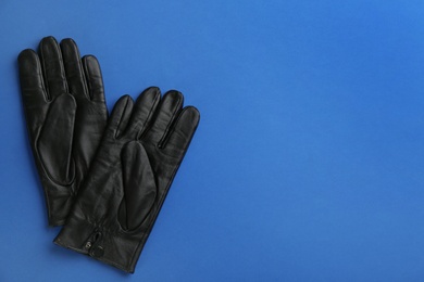 Photo of Pair of stylish leather gloves on blue background, flat lay. Space for text