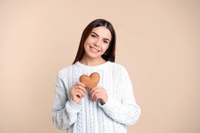 Photo of Portrait of young woman with wooden heart on color background