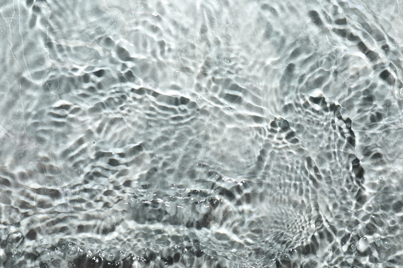 Photo of Rippled surface of clear water on light grey textured background, top view