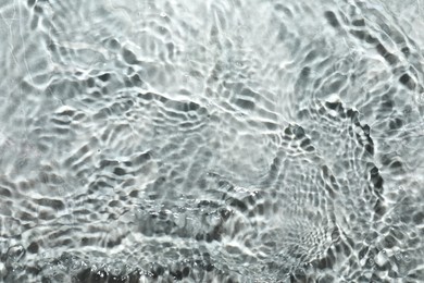 Rippled surface of clear water on light grey textured background, top view